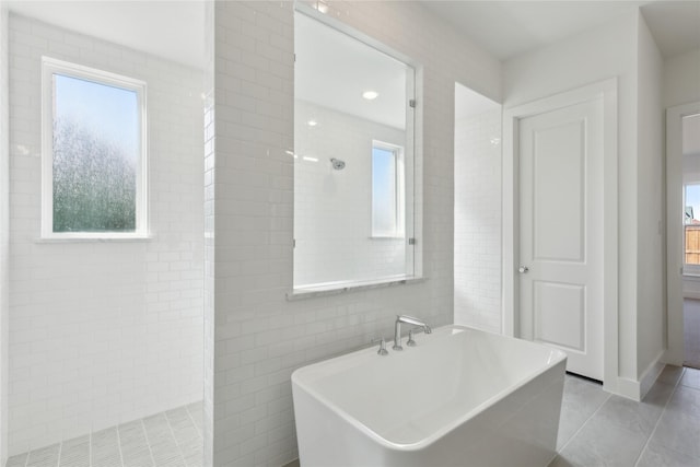 full bath with a soaking tub, a tile shower, tile walls, and tile patterned floors