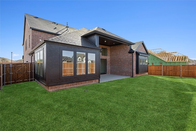 rear view of property featuring a fenced backyard, a patio, a lawn, and brick siding