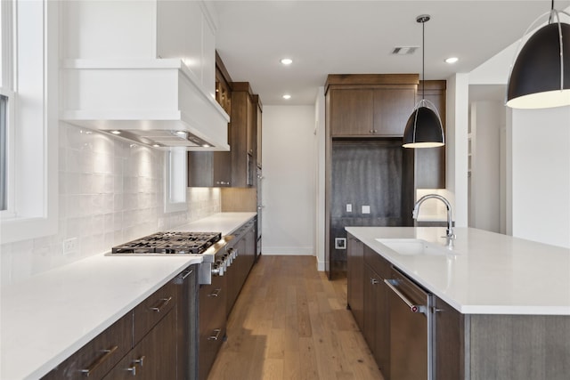 kitchen featuring light countertops, tasteful backsplash, a sink, and light wood-style flooring