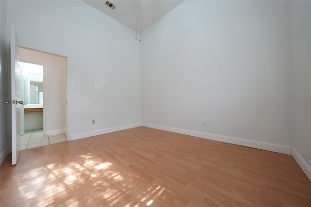 spare room featuring high vaulted ceiling and light hardwood / wood-style floors