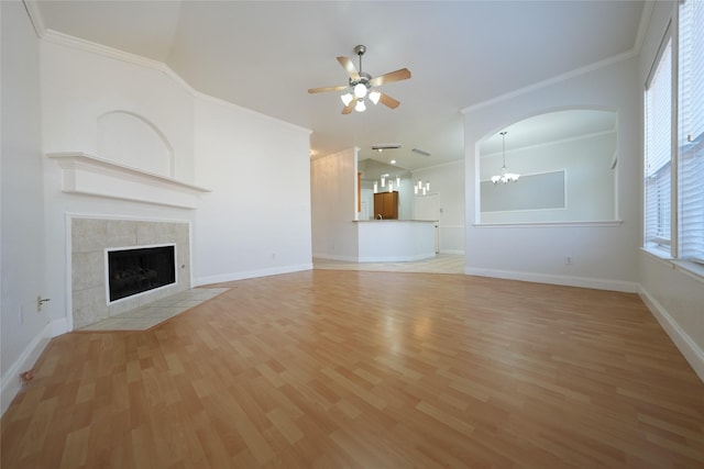 unfurnished living room with hardwood / wood-style flooring, crown molding, a tiled fireplace, and ceiling fan with notable chandelier