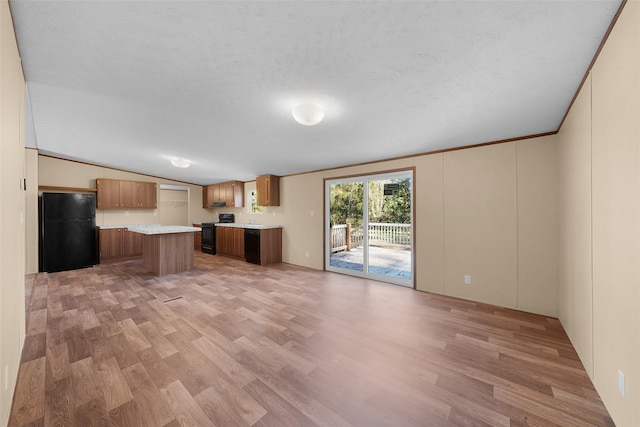 kitchen featuring a kitchen island, lofted ceiling, light hardwood / wood-style flooring, and black appliances