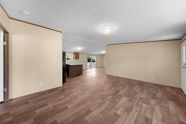 unfurnished living room featuring light hardwood / wood-style floors, a textured ceiling, and ornamental molding