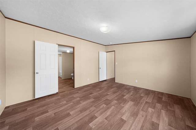 unfurnished bedroom with wood-type flooring, ornamental molding, and a textured ceiling