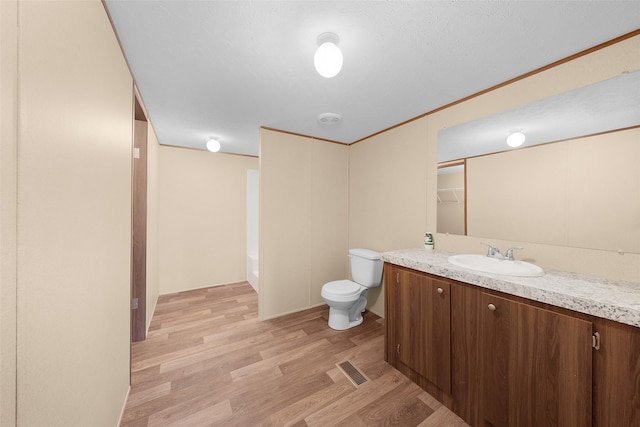 bathroom with hardwood / wood-style floors, toilet, vanity, and a bath