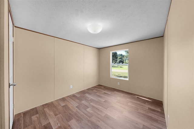 spare room with a textured ceiling and light hardwood / wood-style floors