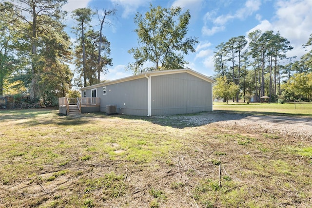 exterior space featuring a wooden deck, a lawn, and central AC