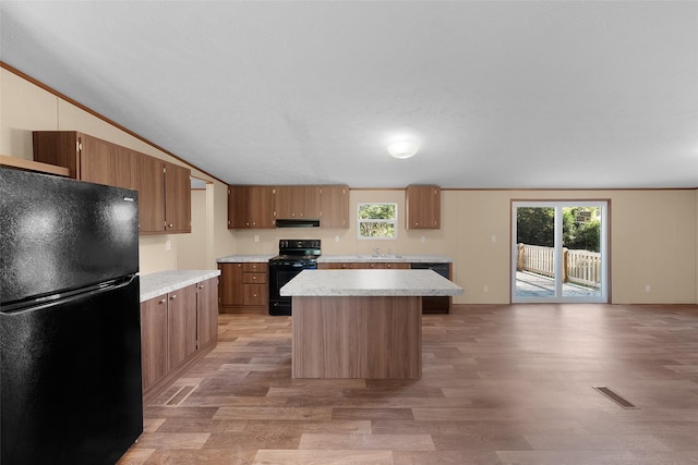 kitchen featuring a wealth of natural light, black appliances, lofted ceiling, and exhaust hood