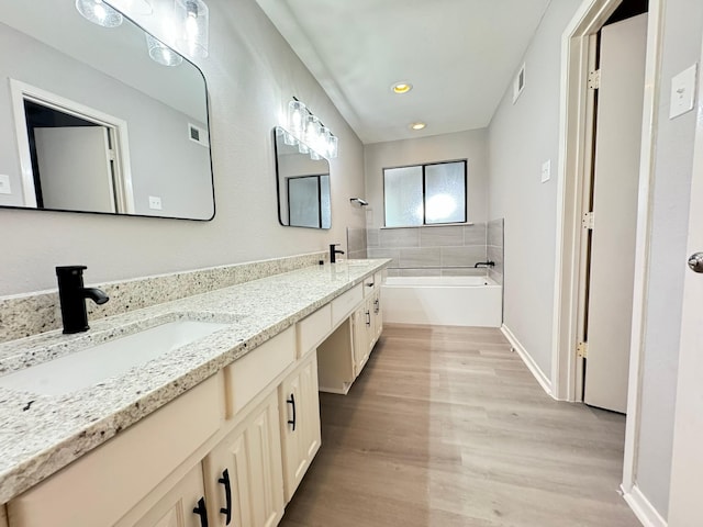 bathroom with hardwood / wood-style floors, vanity, and a bath