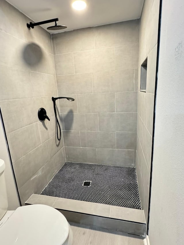 bathroom with toilet and a tile shower