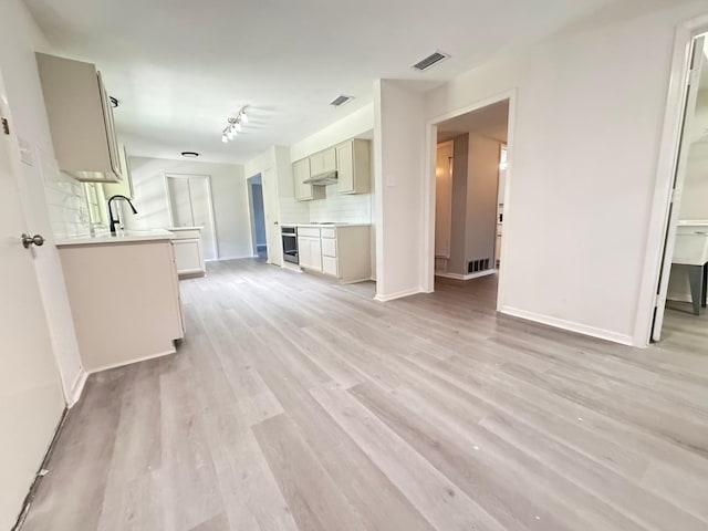 unfurnished living room featuring sink and light hardwood / wood-style flooring