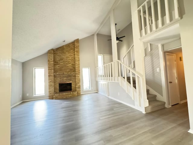 unfurnished living room featuring a fireplace, ceiling fan, plenty of natural light, and hardwood / wood-style flooring