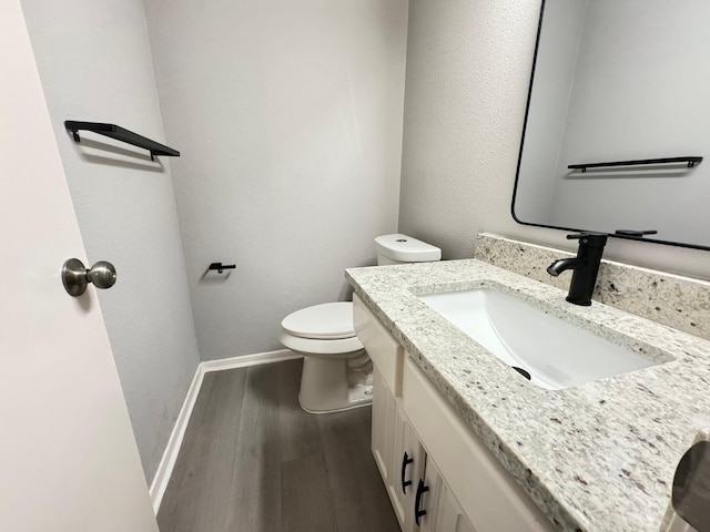 bathroom featuring hardwood / wood-style flooring, toilet, and vanity