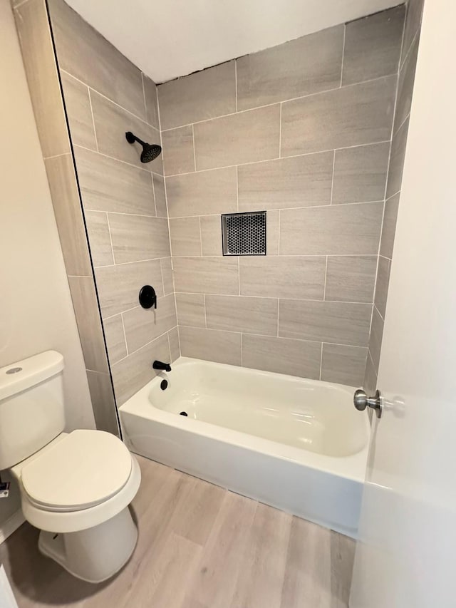 bathroom featuring hardwood / wood-style flooring, toilet, and tiled shower / bath