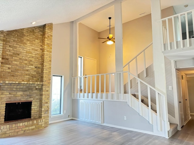 unfurnished living room with ceiling fan, wood-type flooring, a textured ceiling, and vaulted ceiling