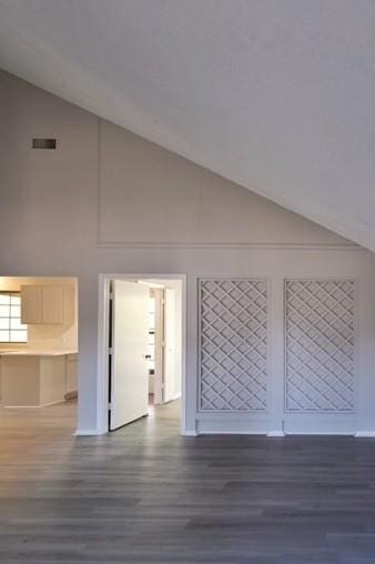 bonus room with dark hardwood / wood-style flooring and high vaulted ceiling