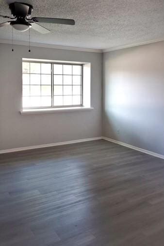 unfurnished room with a textured ceiling, a wealth of natural light, ornamental molding, and dark hardwood / wood-style flooring