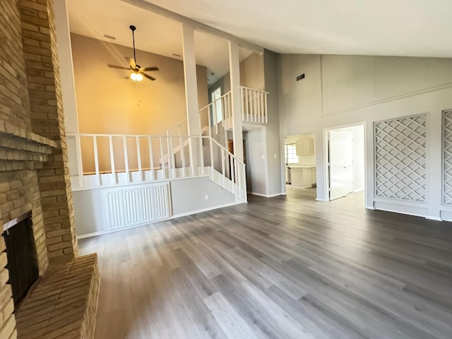 unfurnished living room featuring ceiling fan, high vaulted ceiling, a brick fireplace, and hardwood / wood-style floors