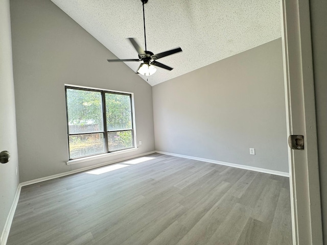 empty room featuring a textured ceiling, ceiling fan, light hardwood / wood-style flooring, and high vaulted ceiling