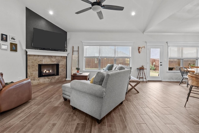 living room featuring vaulted ceiling, a fireplace, and light hardwood / wood-style flooring