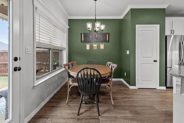 dining room with hardwood / wood-style flooring, a wealth of natural light, ornamental molding, and an inviting chandelier