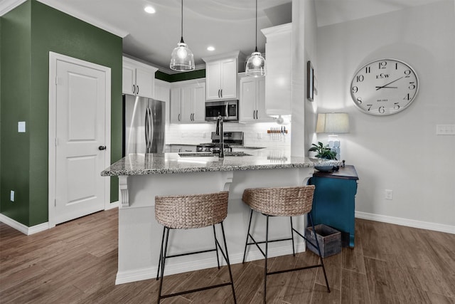 kitchen featuring white cabinets, hardwood / wood-style floors, appliances with stainless steel finishes, and dark stone countertops