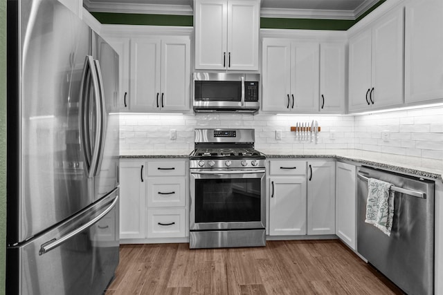 kitchen with light stone counters, white cabinetry, and appliances with stainless steel finishes