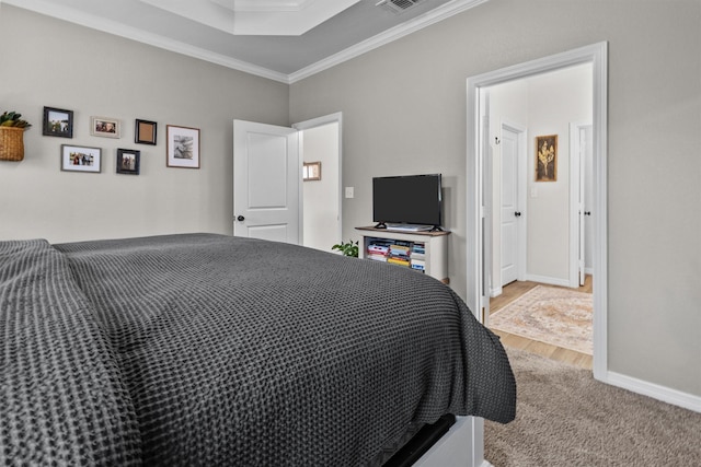 bedroom featuring a tray ceiling, light hardwood / wood-style flooring, and crown molding