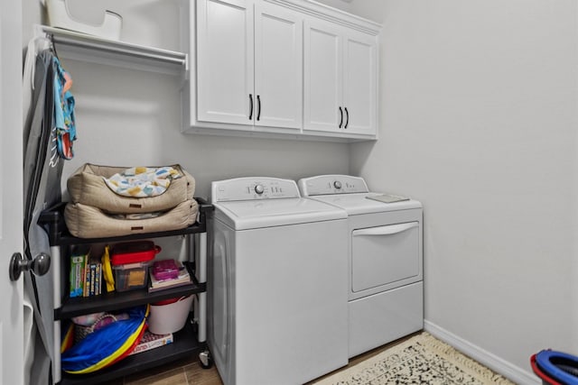 clothes washing area with independent washer and dryer and cabinets