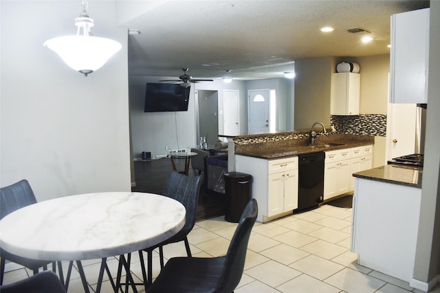 kitchen featuring tasteful backsplash, pendant lighting, kitchen peninsula, black dishwasher, and white cabinetry