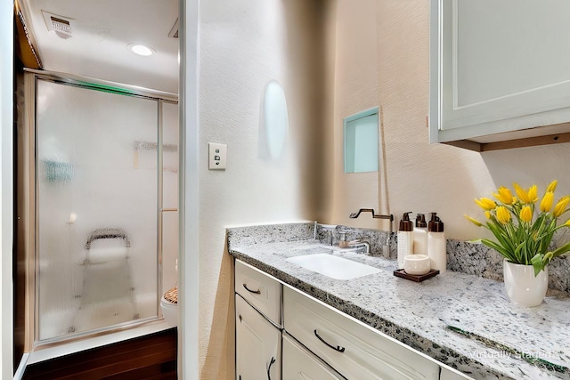 bathroom with a shower with door and vanity