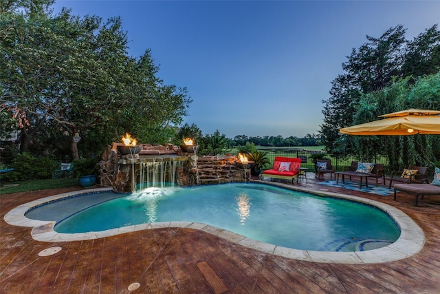 pool at dusk with pool water feature and a deck