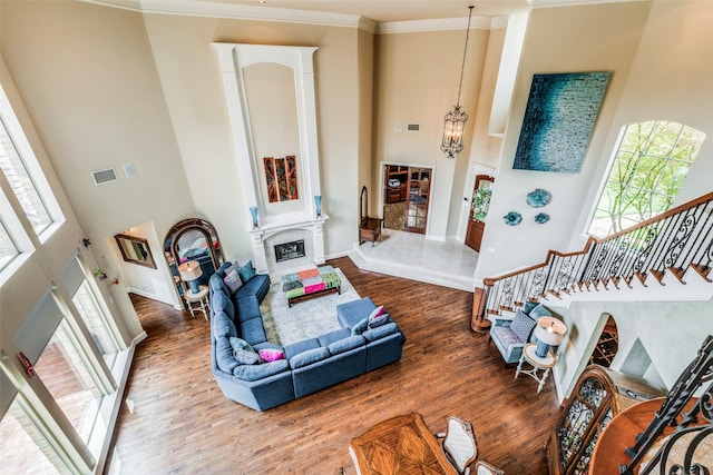 living room featuring hardwood / wood-style flooring, a high ceiling, a notable chandelier, and ornamental molding