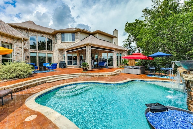 view of pool with a patio, pool water feature, and a hot tub