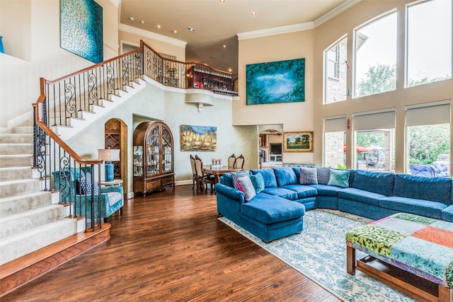 living room featuring crown molding, hardwood / wood-style floors, and a towering ceiling