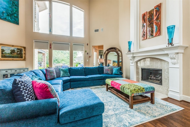 living room featuring a premium fireplace, a high ceiling, and wood-type flooring