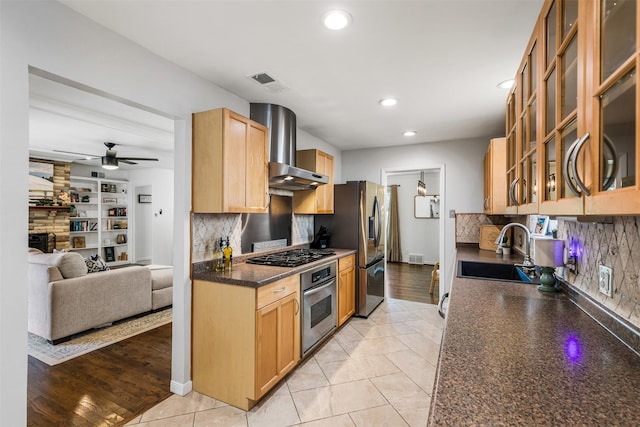 kitchen with appliances with stainless steel finishes, wall chimney exhaust hood, sink, light tile patterned floors, and decorative backsplash