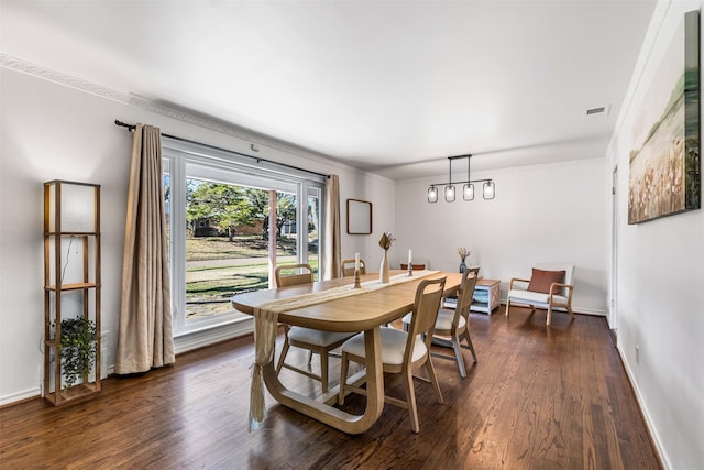 dining space with dark wood-type flooring, ornamental molding, and a notable chandelier