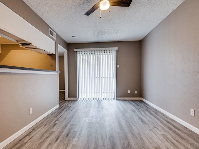 empty room featuring a textured ceiling, ceiling fan, and light hardwood / wood-style flooring