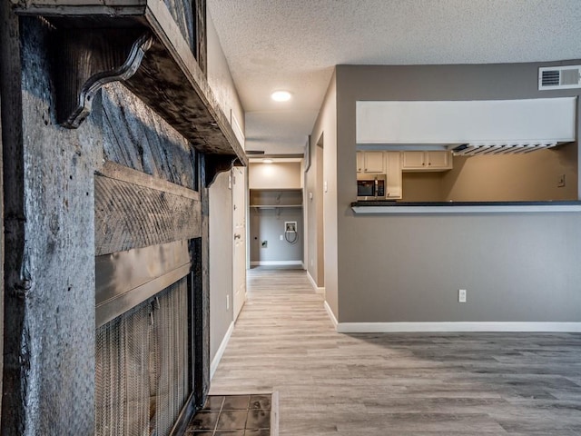 hall featuring light hardwood / wood-style floors and a textured ceiling