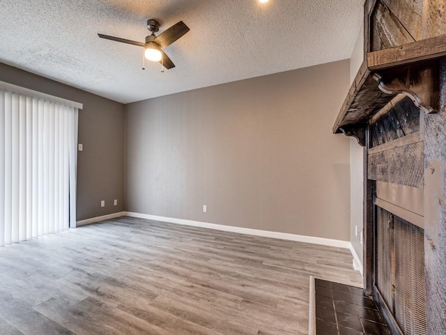 unfurnished living room with ceiling fan, a fireplace, a textured ceiling, and hardwood / wood-style floors