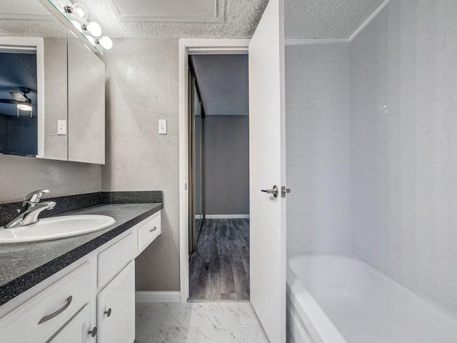 bathroom featuring a textured ceiling, a bathtub, and vanity