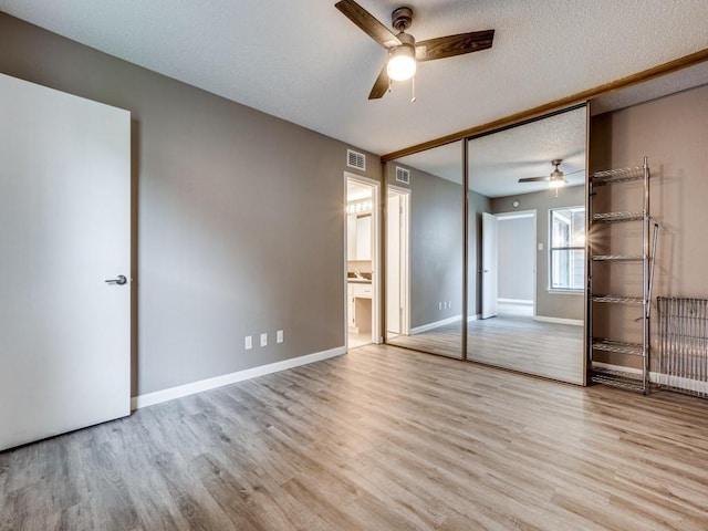 unfurnished bedroom featuring ceiling fan, a textured ceiling, a closet, and light hardwood / wood-style flooring