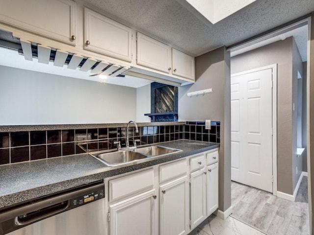 kitchen featuring decorative backsplash, sink, white cabinets, and stainless steel dishwasher