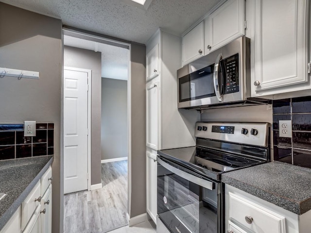 kitchen featuring tasteful backsplash, light wood-type flooring, appliances with stainless steel finishes, a textured ceiling, and white cabinets