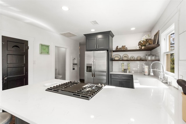 kitchen featuring stainless steel refrigerator with ice dispenser, sink, black gas cooktop, and kitchen peninsula