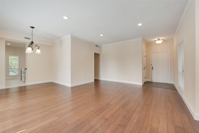 unfurnished room with light wood-type flooring, an inviting chandelier, and ornamental molding