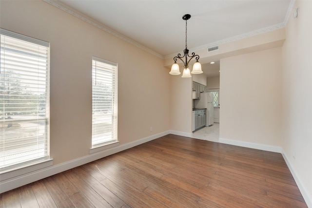 unfurnished dining area with a chandelier, ornamental molding, and hardwood / wood-style flooring