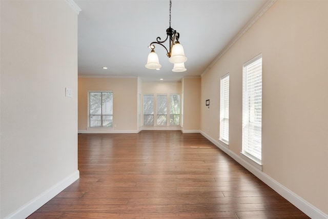 empty room featuring hardwood / wood-style floors, crown molding, and an inviting chandelier