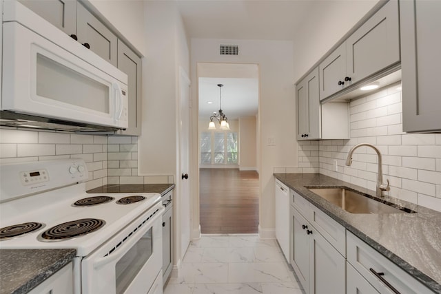 kitchen featuring sink, tasteful backsplash, dark stone counters, and white appliances